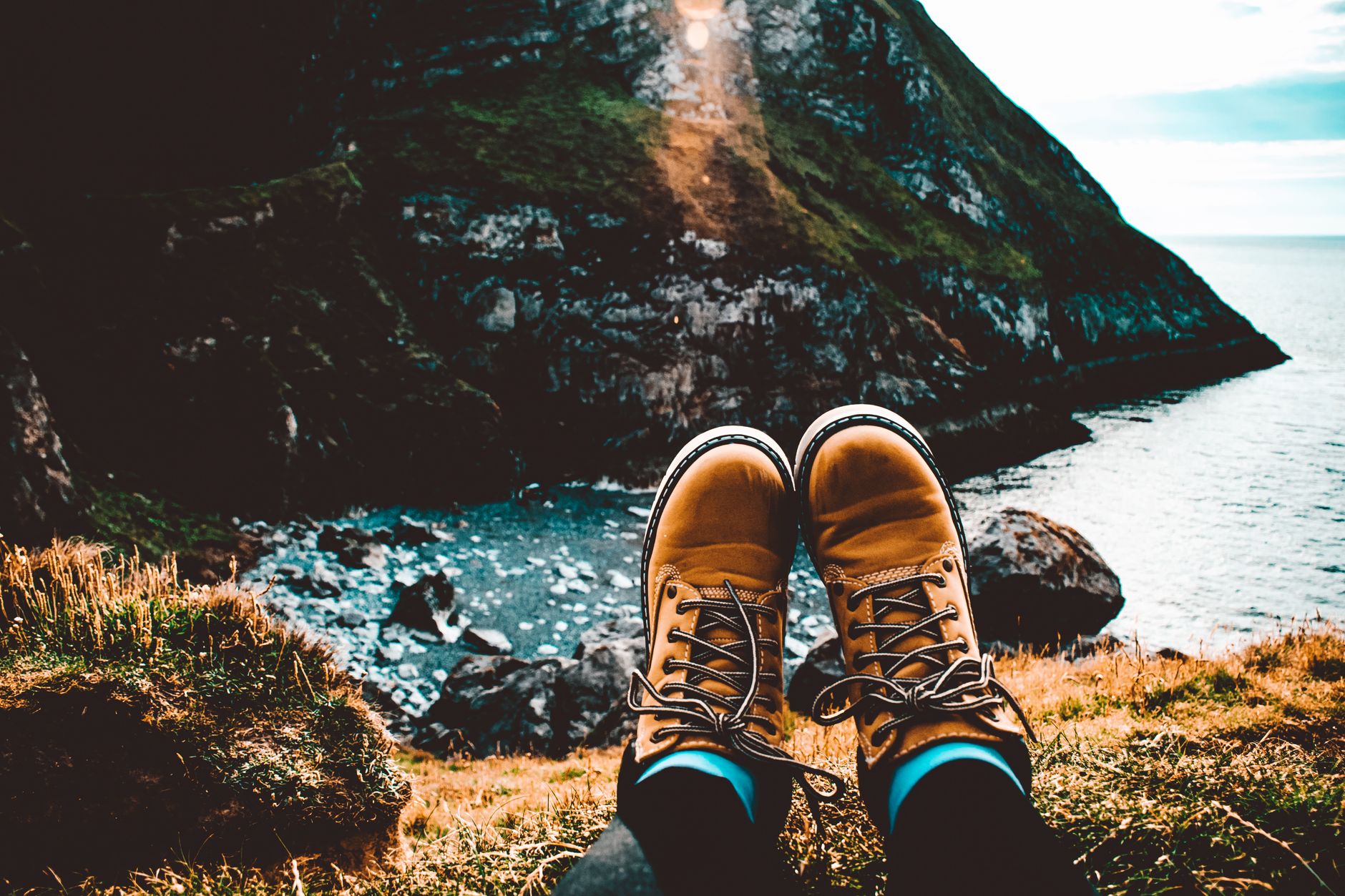 A person is wearing a nike hiking boots while sitting near the ocean