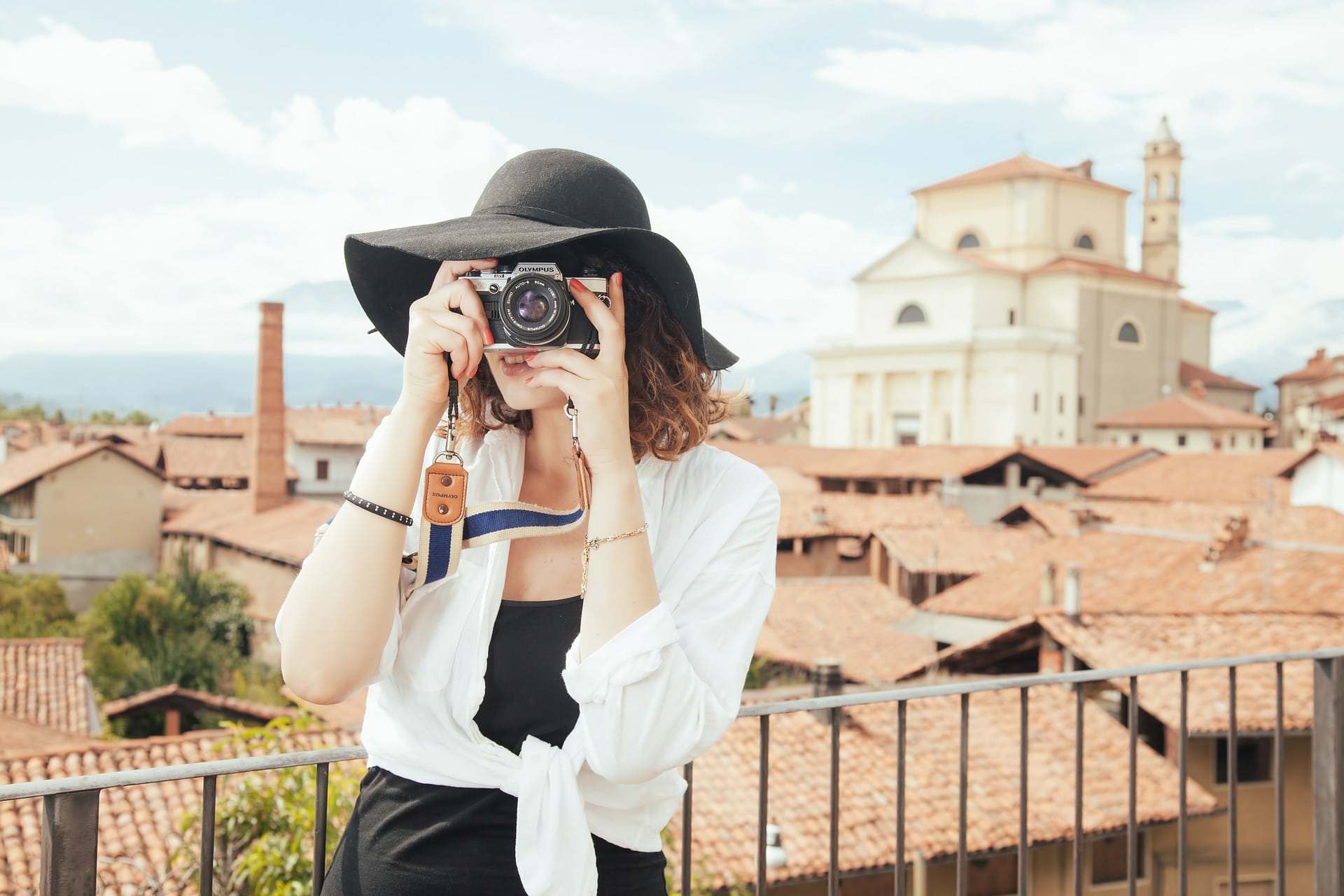 Girl holding the best travel camera is taking photos of the beautiful view that she saw