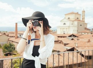 Girl holding the best travel camera is taking photos of the beautiful view that she saw